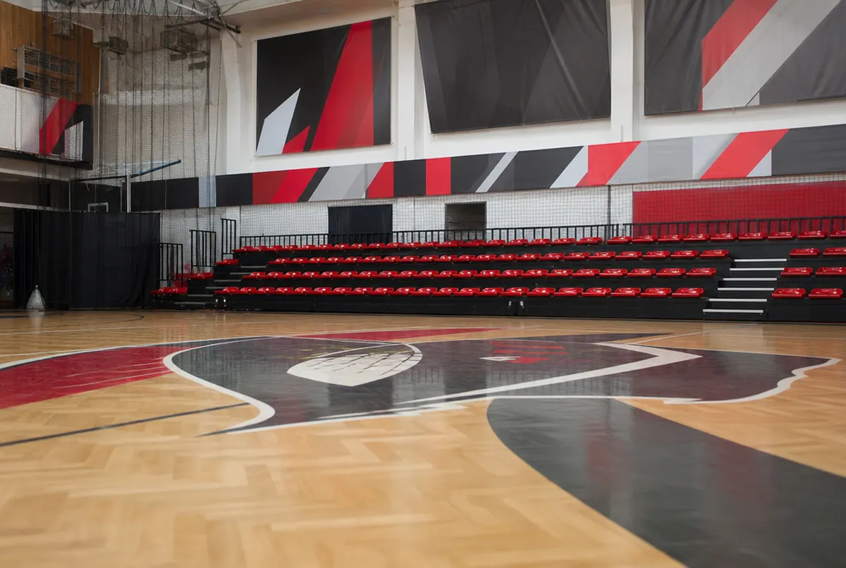Hala sportowa z logo klubu na parkiecie i banerami sponsorów