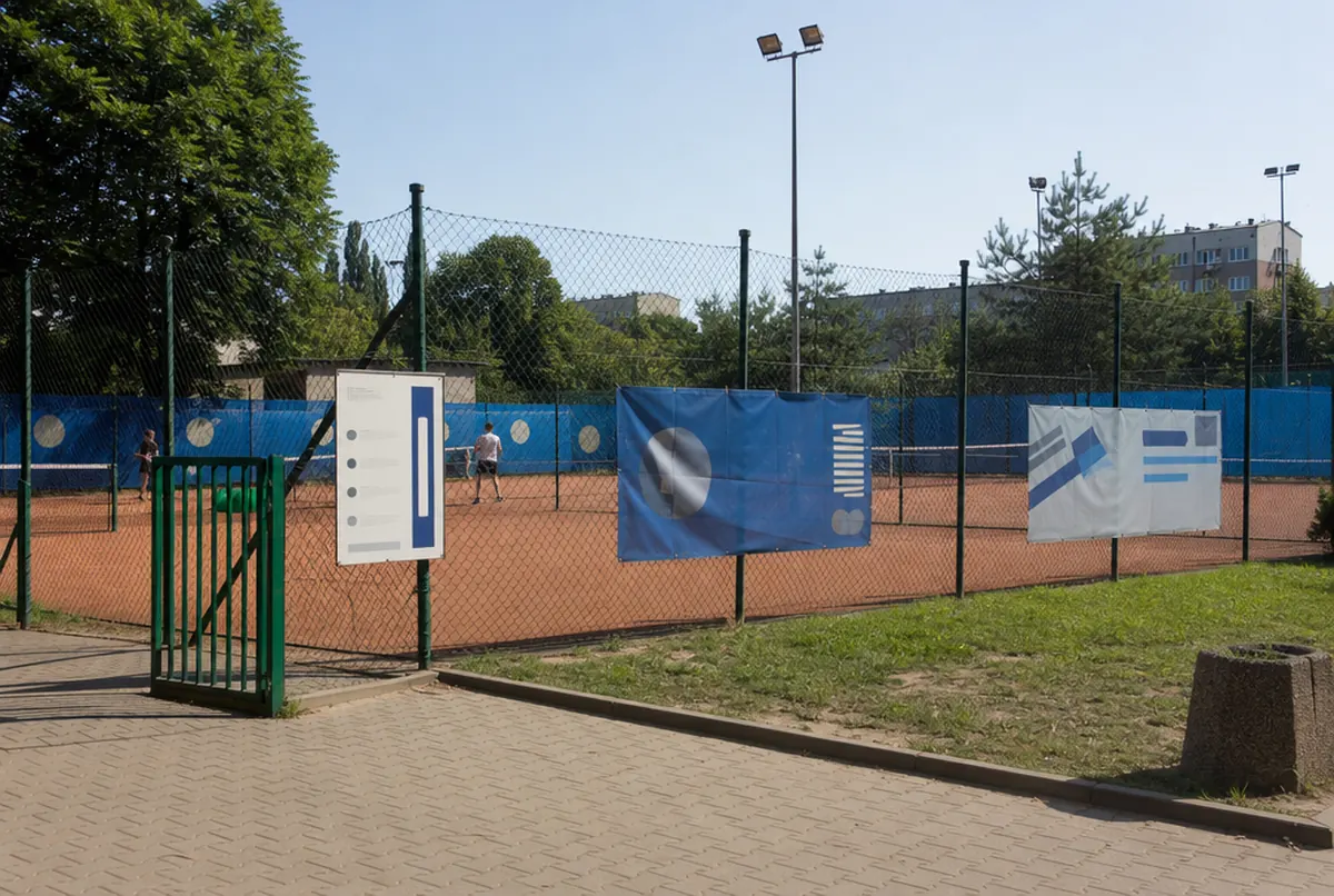 Korty tenisowe MOSiR z blenderami i banerami na ogrodzeniu