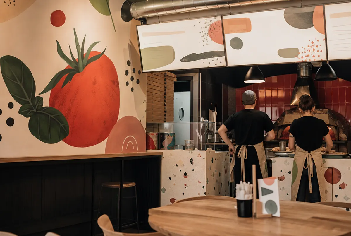 Sala pizzerii z grafiką ścienną i menu na płycie przy ladzie