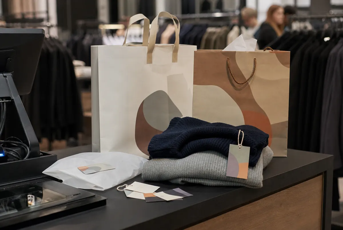 Torby papierowe i metki produktowe przy kasie salonu odzieżowego