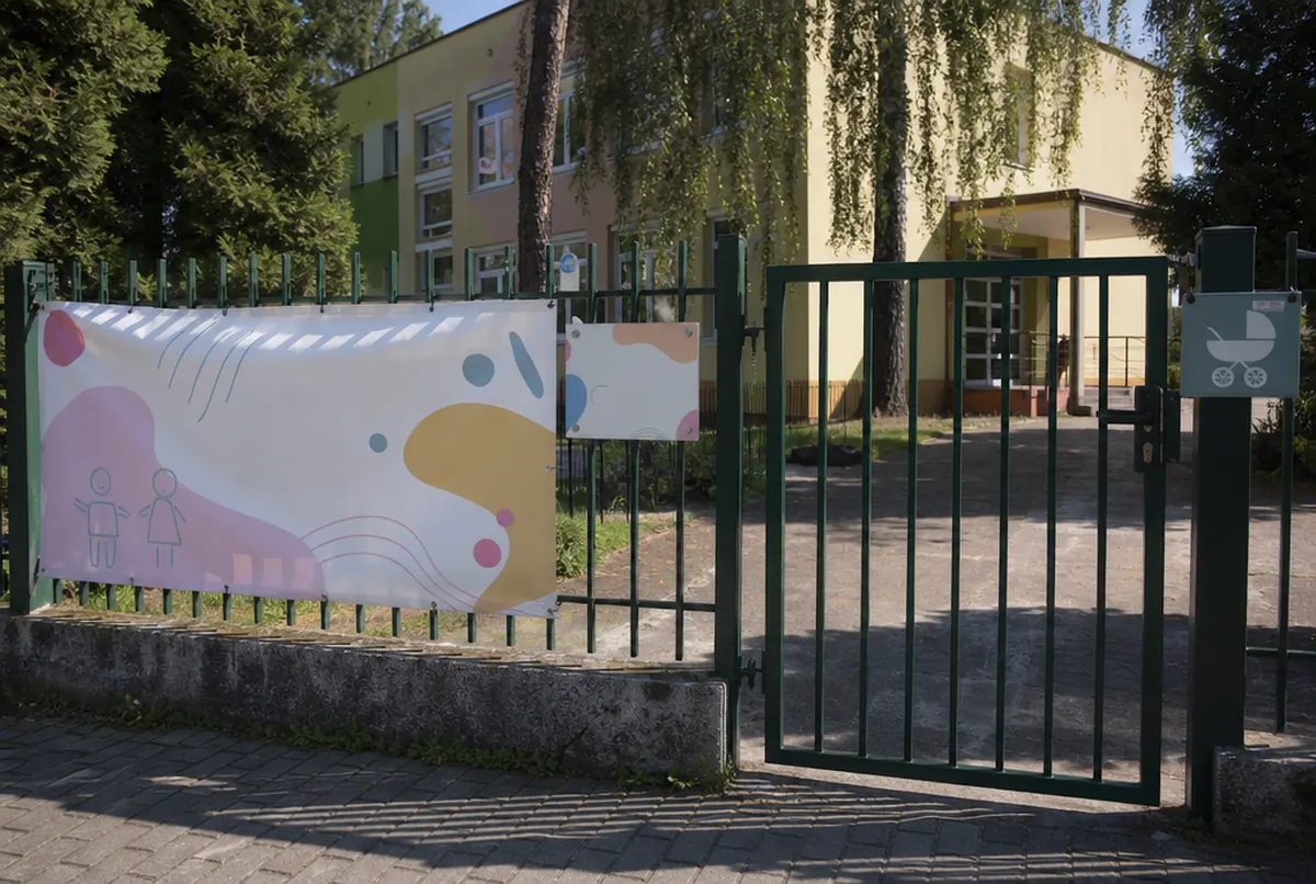 Baner rekrutacyjny i tablica z godzinami na ogrodzeniu żłobka