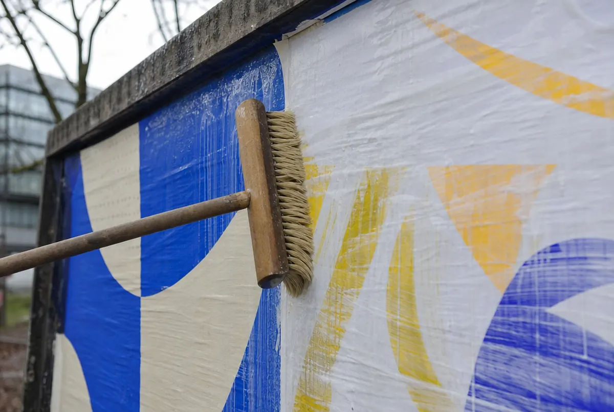 Bürste glättet eine frische Blueback-Plakatbahn, Stoß zwischen den Bogen sichtbar