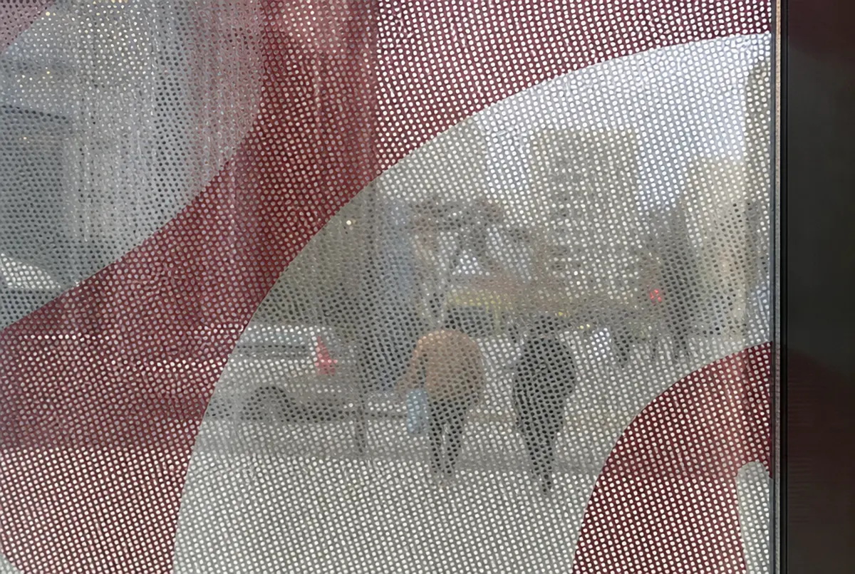 Detalle del vinilo OWV: retícula de agujeros y la calle vista a través