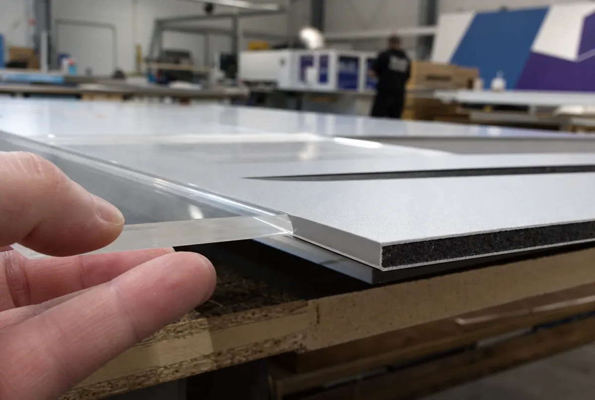 Close-up of a routed acrylic edge with chamfer and a composite panel edge showing its core