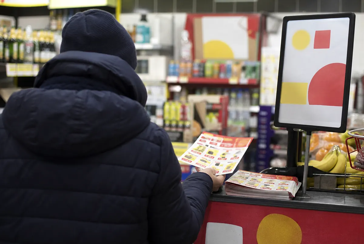 Une cliente prend un prospectus promotionnel au comptoir d'une épicerie