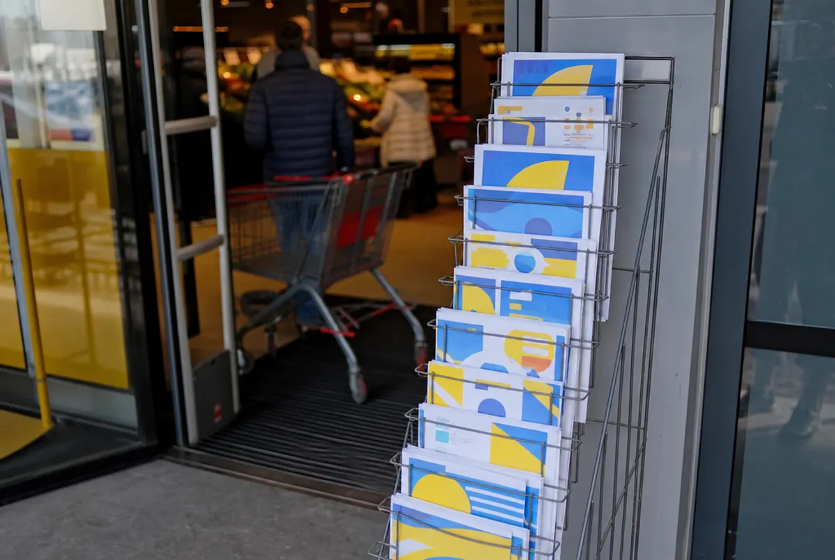 Présentoir à prospectus promotionnels à l'entrée d'un supermarché régional