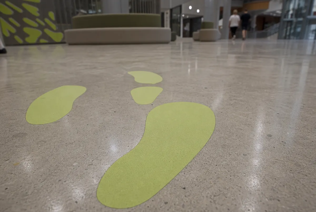 Die-cut lime footprints on a polished concrete floor with a matte laminate
