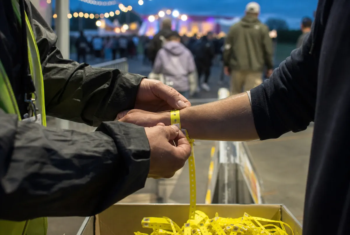 Checking a numbered entry wristband on a guest's wrist at a festival gate