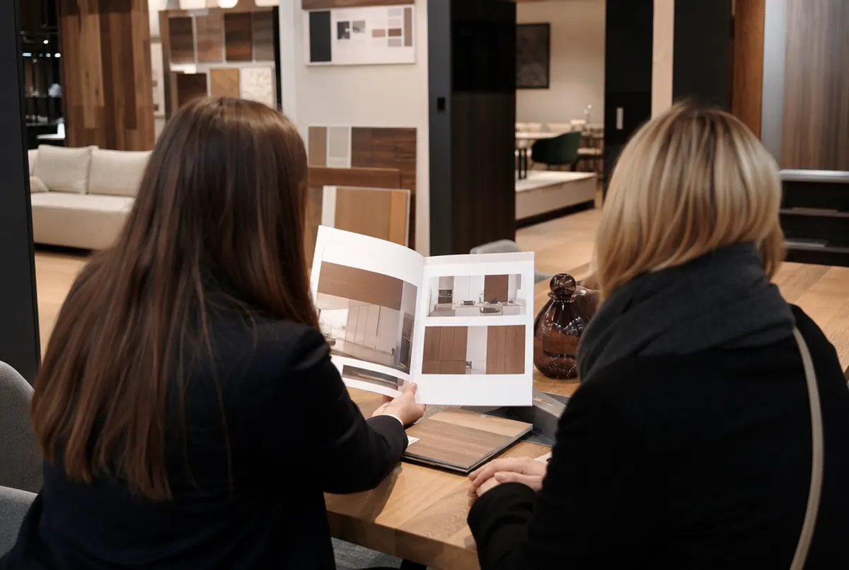 Verkäufer zeigt einem Kunden einen offenen A4-Produktkatalog im Showroom