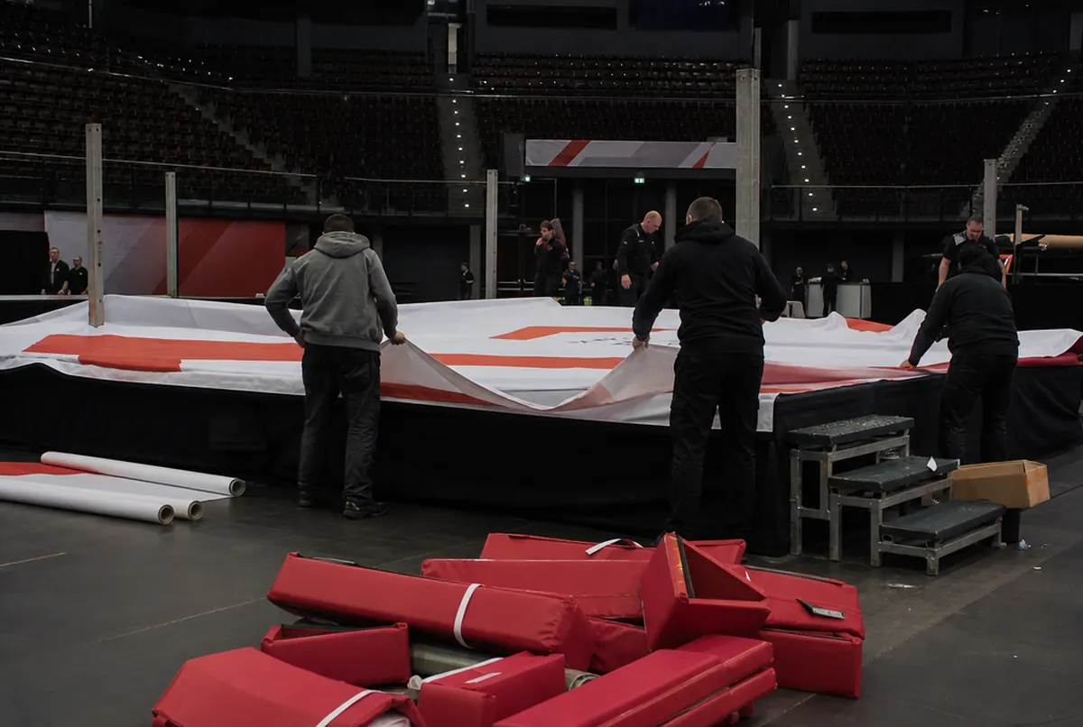 Crew stretching a printed mat cover over a boxing ring before the gala