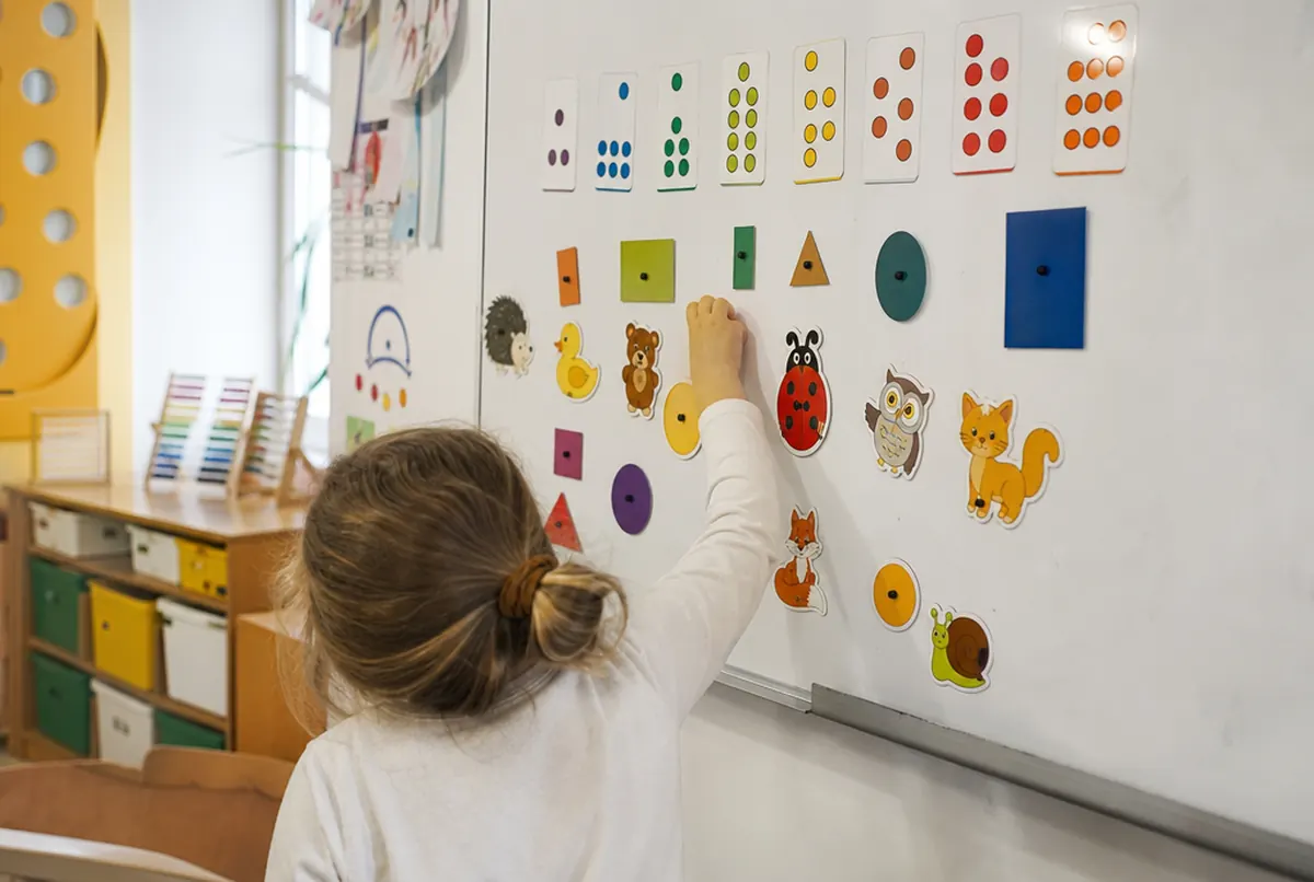 Juego educativo de imanes con formas y animales en la pizarra blanca de un aula