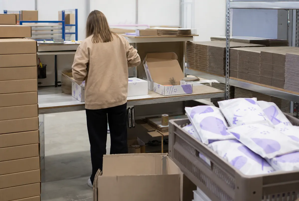 Puesto de embalaje en el almacén de una tienda online con cajas blancas impresas