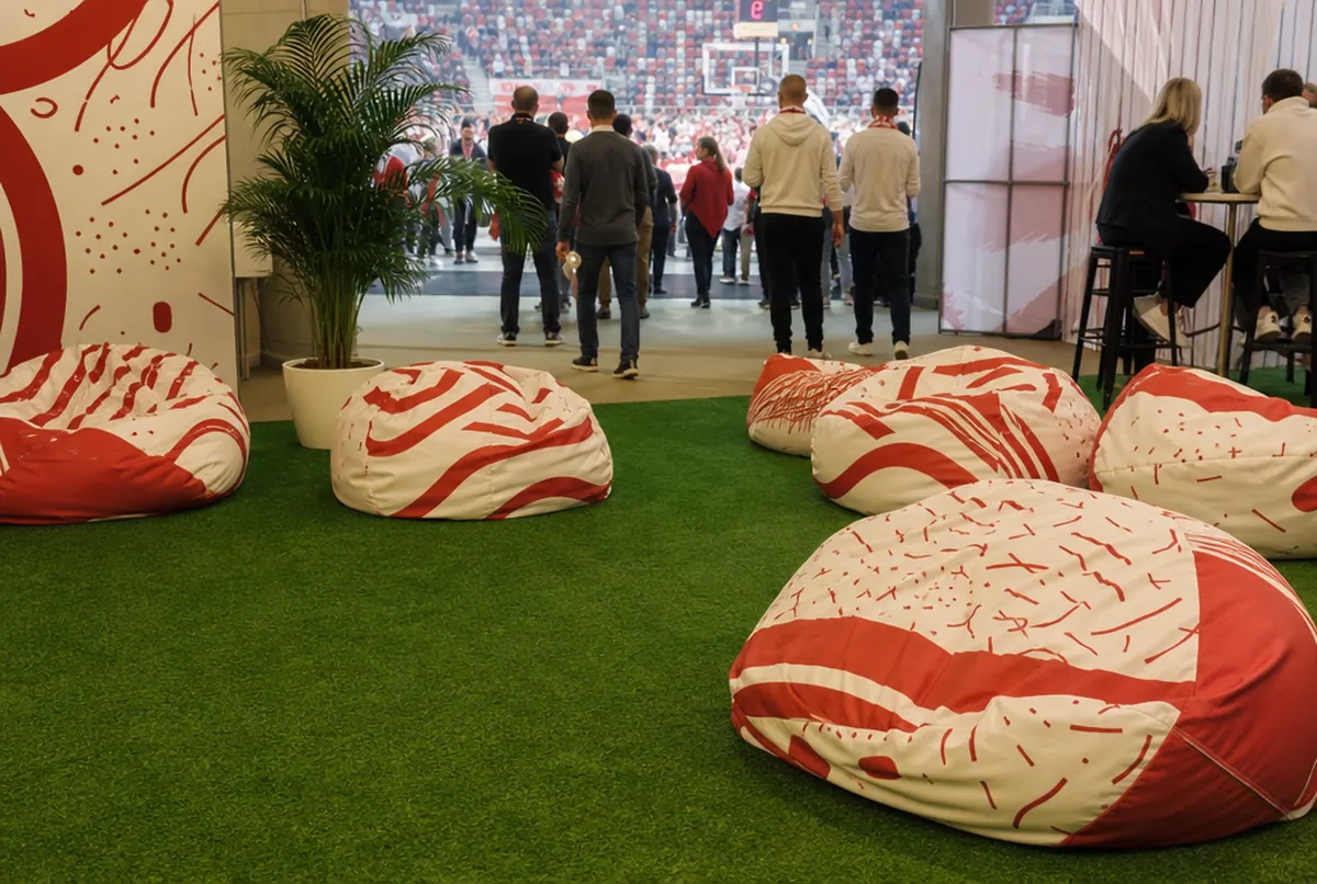 Bedruckte Sitzsäcke auf Kunstrasen in der Fanzone einer Sporthalle