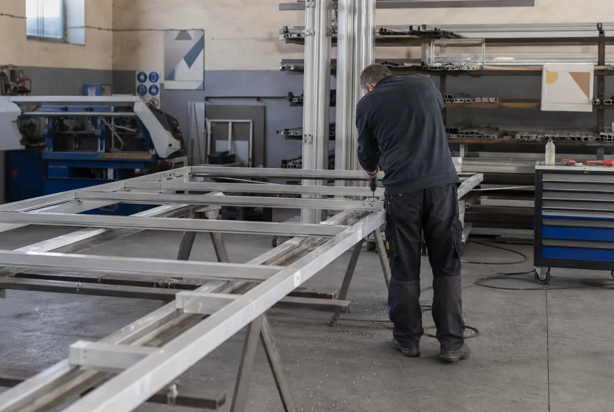 Drilling mounting holes in an aluminium tension frame on trestles in the workshop