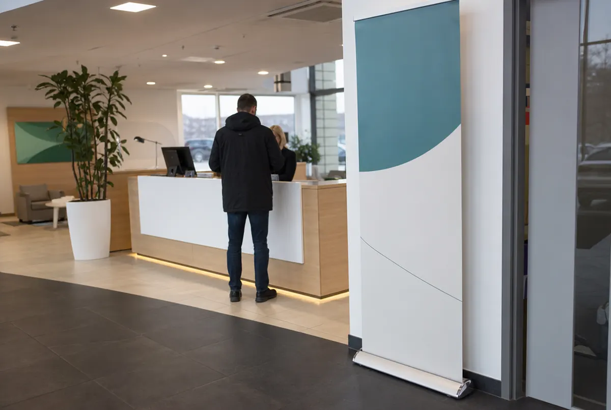 Roll-up con base de aluminio y gráfica vertical en la recepción de un concesionario