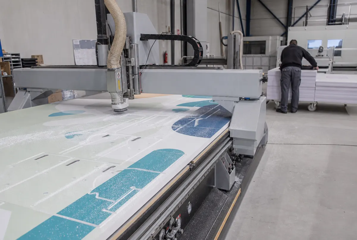 CNC-Fräse schneidet Hakenlöcher in eine bedruckte PVC-Platte für Displays