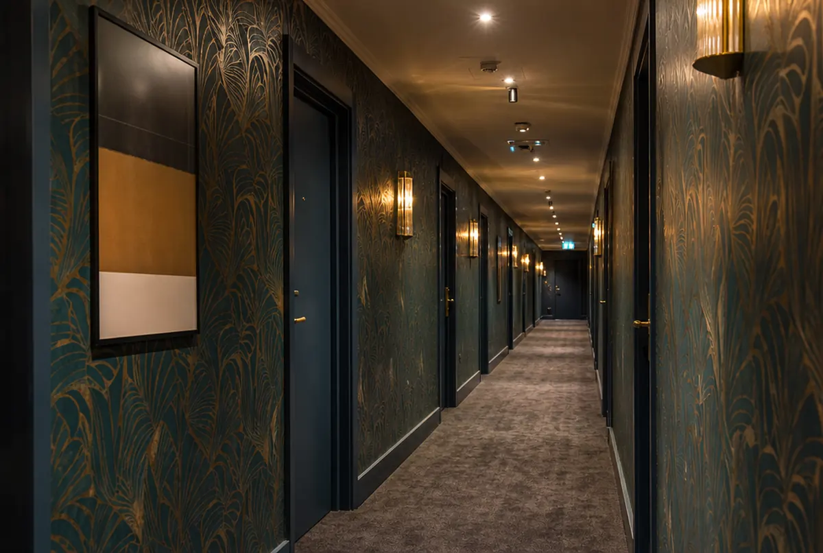 Hotelflur mit Rapporttapete im Pflanzenmuster in Petrol und Gold