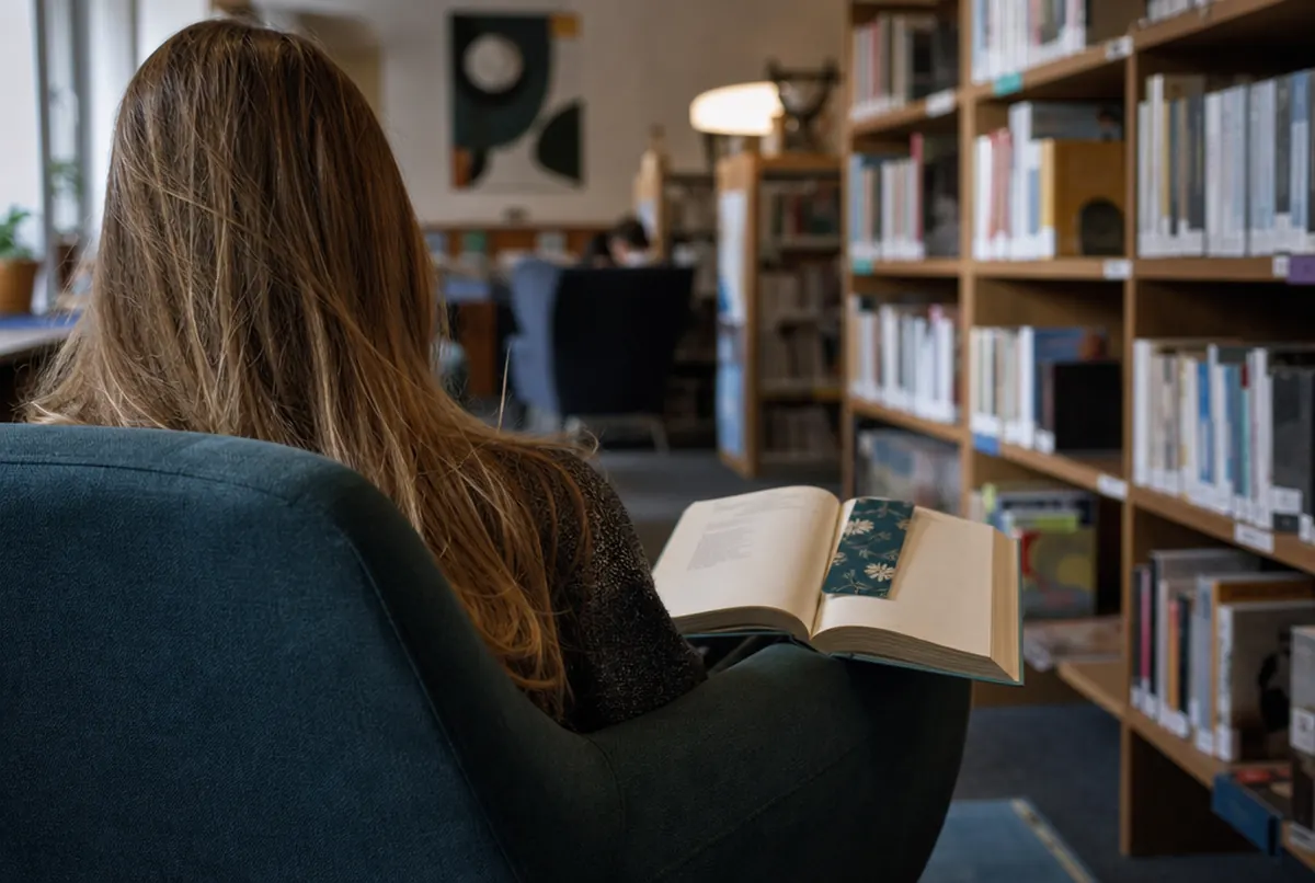 Marcapáginas impreso en el libro abierto de un lector en una biblioteca